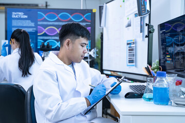 Scientist in laboratory conducting medical research using modern science and technology while taking note for doctor and clinical analysis.