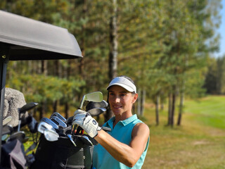 Woman organizing golf clubs near golf cart sunlit forested area