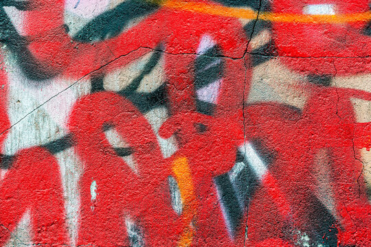 abstract expressive spray drawing in red and black colors on the cracked stucco wall of city.