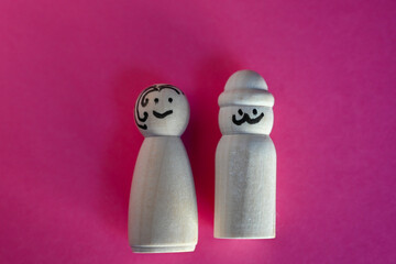 wooden peg dolls symbolizing man and woman on pink background