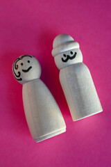 wooden peg dolls symbolizing man and woman on pink background