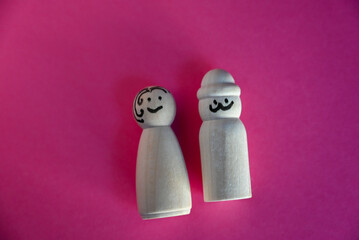 wooden peg dolls symbolizing man and woman on pink background