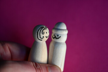 wooden peg dolls symbolizing man and woman on pink background