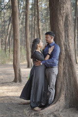 A romantic Indian couple embracing lovingly with closed eyes in a serene pine forest