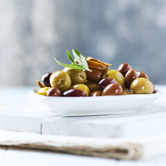 Various olives on bright wooden background. Close up. Copy space.	