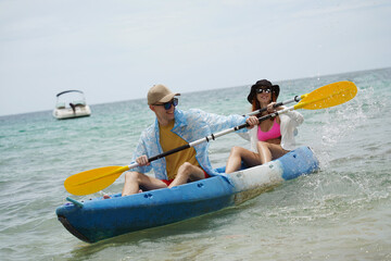 The young couple are happily navigating together in a light blue kayak with yellow paddles