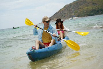 The young couple are happily navigating together in a light blue kayak with yellow paddles