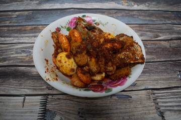 A delicious meal with shrimp, eggs, fish, and tempeh drizzled with savory red chili sauce.