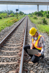 An industrial inspector is meticulously examining a railroad track, employing modern technology on...