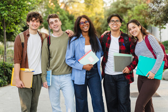 Portrait of cheerful international exchange University students looking at camera smiling outdoors together laughing after lectures