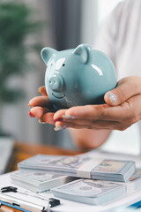 Businesswoman saving money with piggy bank and coins on desk, financial planning and investment...