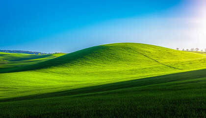 Obraz premium Serene green rolling hills under a clear blue sky with sunlight