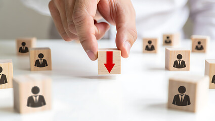 Human resources reduction concept with hand choosing a cube representing a career decline.