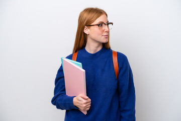 Young student redhead woman isolated on white background looking to the side