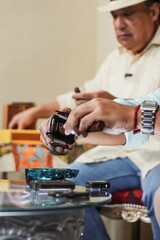 Man cutting cigar with cutter while sitting with friend