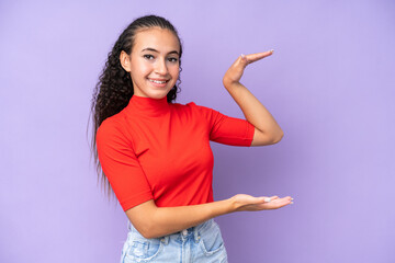 Young woman isolated on purple background holding copyspace to insert an ad