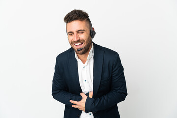 Telemarketer man working with a headset isolated on white background smiling a lot