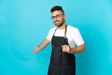 Barber man in an apron extending hands to the side for inviting to come