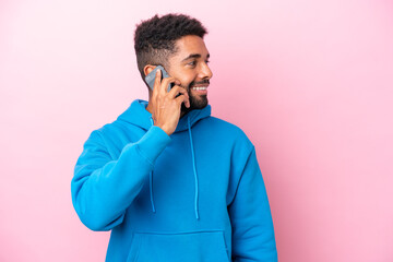 Fototapeta premium Young Brazilian man isolated on pink background keeping a conversation with the mobile phone with someone