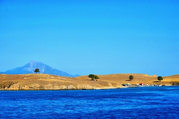 Greek sandy beach with trees and beautiful blue sea water