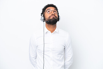 Telemarketer Brazilian man working with a headset isolated on white background and looking up