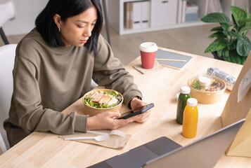 Asian woman eating healthy meal while working, Businesswoman having a lunch break at the office