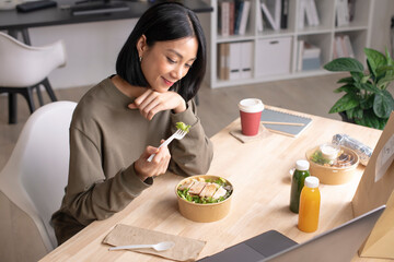 Asian woman eating healthy meal while working, Businesswoman having a lunch break at the office