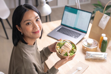 Asian woman eating healthy meal while working, Businesswoman having a lunch break at the office