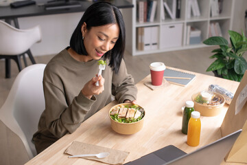 Asian woman eating healthy meal while working, Businesswoman having a lunch break at the office