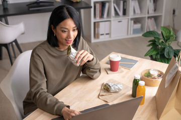 Asian woman eating healthy meal while working, Businesswoman having a lunch break at the office.