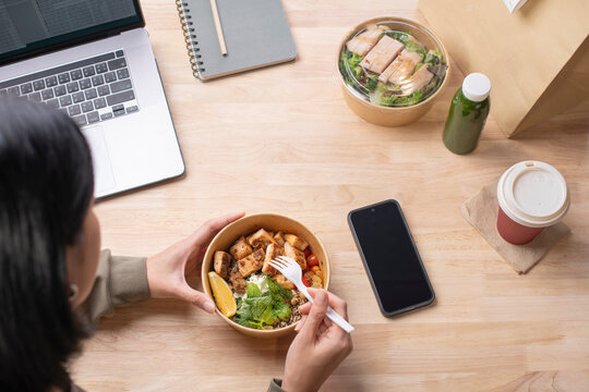 Asian woman eating healthy meal while working, Businesswoman having a lunch break at the office