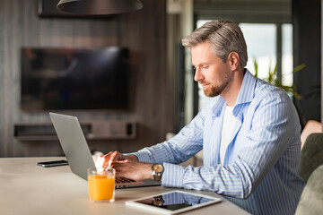 Young businessman sitting at a table at home working on a laptop