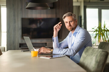 Young businessman sitting at a table at home working on a laptop