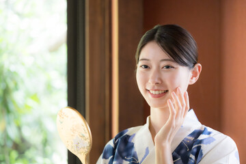 Woman in yukata checking her skin in the mirror Beauty and beauty image of kimono
