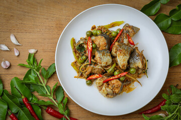 Spicy stir-fried catfish (Pad Cha Pla Dook) on a white plate, a popular and flavorful Thai dish. The dish features pieces of catfish stir-fried with herbs, spices, chili peppers and Original Thai food