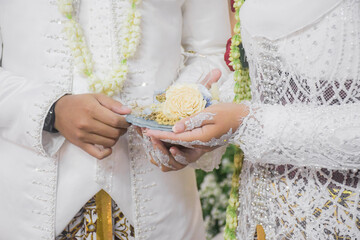 Bride and groom exchanging rings during a traditional Indonesian wedding ceremony, symbolizing their commitment and love. Asian muslim wedding	
