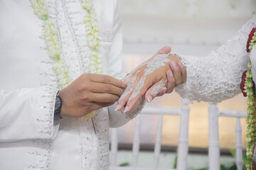 Bride and groom exchanging rings during a traditional Indonesian wedding ceremony, symbolizing their commitment and love. Asian muslim wedding	
