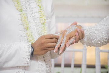 Bride and groom exchanging rings during a traditional Indonesian wedding ceremony, symbolizing their commitment and love. Asian muslim wedding	

