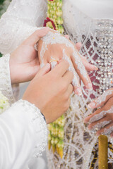 Bride and groom exchanging rings during a traditional Indonesian wedding ceremony, symbolizing their commitment and love. Asian muslim wedding	

