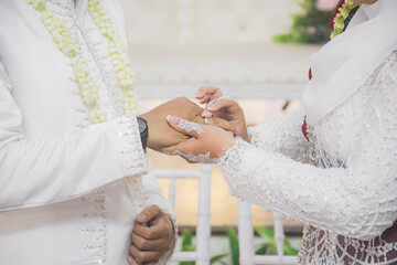 Bride and groom exchanging rings during a traditional Indonesian wedding ceremony, symbolizing their commitment and love. Asian muslim wedding	
