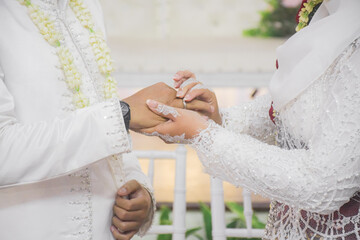 Bride and groom exchanging rings during a traditional Indonesian wedding ceremony, symbolizing their commitment and love. Asian muslim wedding	
