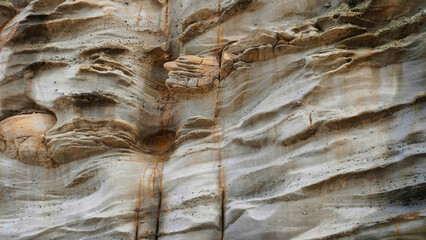 Textured rock formations displaying natural erosion patterns in a layered landscape near the ocean