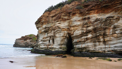 Ghosties Beach Caves NSW Australia.Stunning coastal rock formations along a serene beach at dawn near a cave entrance