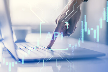 Businessperson interacting with digital API interface over laptop with financial data overlay on light office background.