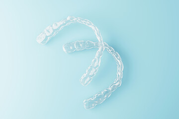 Transparent dental aligners on blue gradient background showcasing modern orthodontic treatment concept in clean minimal design style. 3D Rendering