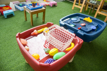 Set of different cute toys in children's playground. Preschool building exterior with playground and toys on a sunny day