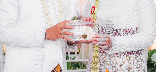 Bride and groom exchanging rings during a traditional Indonesian wedding ceremony, symbolizing their commitment and love. Asian muslim wedding