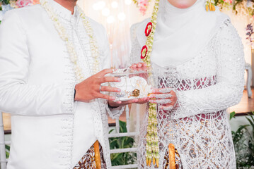 Bride and groom exchanging rings during a traditional Indonesian wedding ceremony, symbolizing their commitment and love. Asian muslim wedding