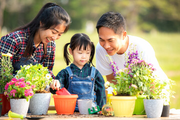 Family child girl helping parent care plant flower in garden. Young people mother, father and daughter gardening outdoor sunny nature background. Happy and enjoy in spring and summer day