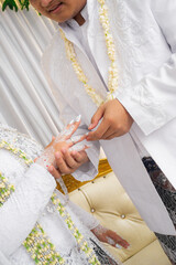 Bride and groom exchanging rings during a traditional Indonesian wedding ceremony, symbolizing their commitment and love. Asian muslim wedding
